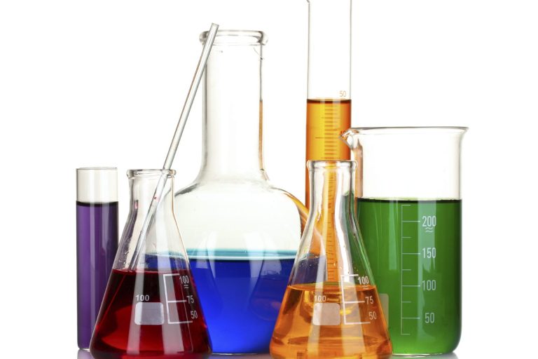 Chemistry lab glassware with liquids in various colours: purple, blue, orange, and green.