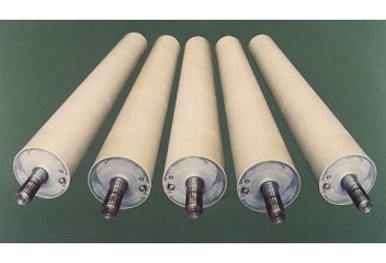 Five ceramic coated cylindrical rollers with metal ends, arranged in a line on a green surface.