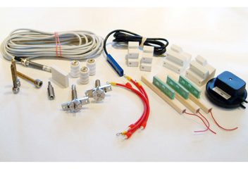 Assorted spare parts for corona treaters, including wires, connectors, and mounting accessories.