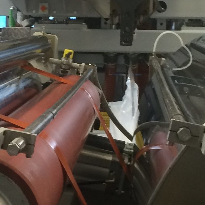 Close-up of ozone applicators above rollers on an extrusion coating line.